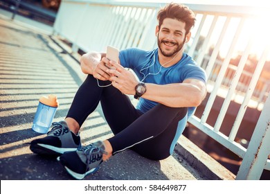 Young male jogger athlete training and doing workout outdoors in city.
