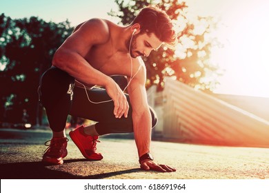 Young male jogger athlete training and doing workout outdoors in city.