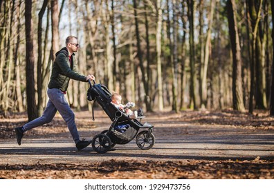 a young male jogging in a park with a baby stroller 