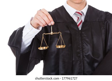 Young Male Judge Holding Golden Scales And Book Over White Background