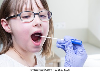 Young Male Laryngologist Doctor Using Tongue Depressor And Swab To Collect Culture Sample From Child Patient Throat