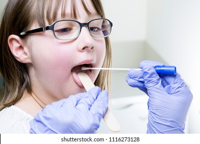 Young Male Laryngologist Doctor Using Tongue Depressor And Swab To Collect Culture Sample From Child Patient Throat