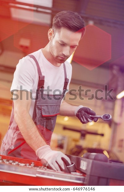 Young male maintenance engineer arranging tools\
in drawer at car workshop