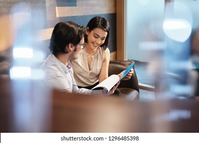 Young Male Manager Working In Modern Office Cafeteria And Meeting Female Colleague. Busy Business Man And Woman At Work In Corporate Coworking Space Lounge. Team Of Businessman And Businesswoman