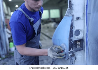 young male master repairs the body of a car van, auto body repair. - Powered by Shutterstock