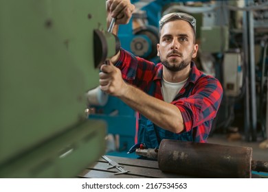 Young male mechanic with safety glasses on his head operating the machinery