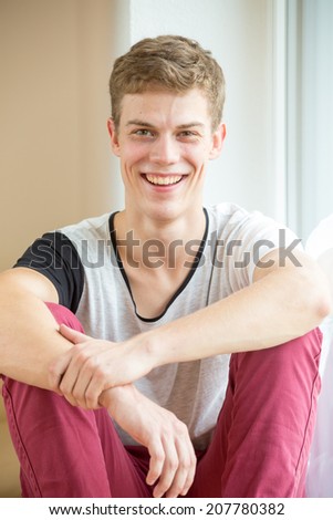 A young male model is laughing in a bright, modern environment