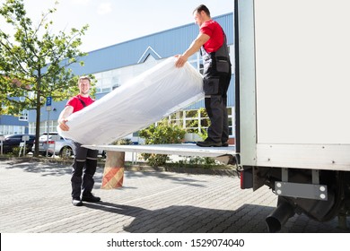 Young Male Movers Unloading The Wrapped Mattress From Moving Truck - Powered by Shutterstock