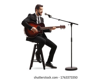 Young Male Musician With An Electric Guitar Sitting On A Chair And Playing Isolated On White Background