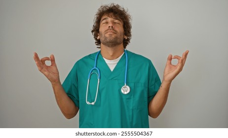 Young, male nurse in green scrubs with stethoscope meditates peacefully with eyes closed, isolated against a plain white background - Powered by Shutterstock