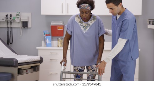 Young Male Nurse Helps Senior Black Woman Walk With Crutches