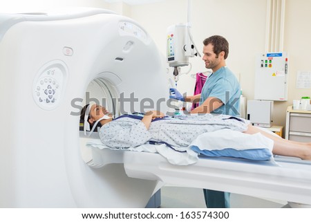 Young male nurse preparing patient for CT scan test in examination room