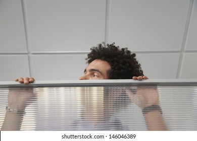 Young Male Office Worker Peering Over Cubicle Wall In The Office