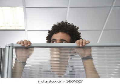 Young Male Office Worker Peering Over Cubicle Wall In The Office