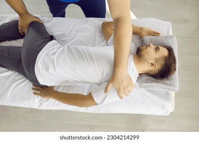 Young male osteopath is working on the spinal lumbar region of young patient to align the vertebrae. Osteopath kneads the lower and upper part of the spine of patient lying on couch. - Powered by Shutterstock