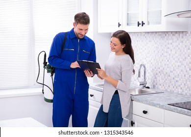 Young Male Pest Control Worker Showing Invoice To Woman In Domestic Kitchen
