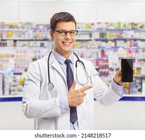 Young Male Pharmacist Showing A Mobile Phone Inside A Chemist Store