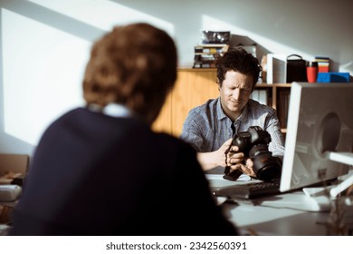 Young male photographer having a meeting with a client in his office - Powered by Shutterstock