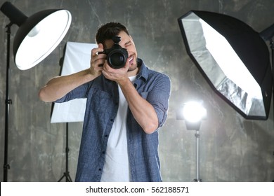 Young Male Photographer In Studio With Professional Lighting Equipment