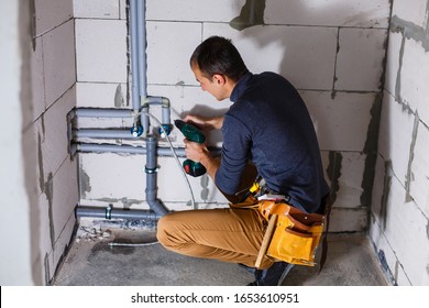 Young Male Plumber makes wiring of sewer pipes