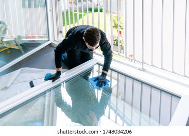 A Young Male Professional Cleaner Cleaning A Large Fold-down Window