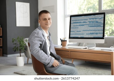 Young male programmer working with computer in modern home office