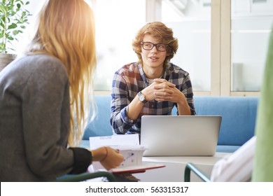 Young male pupil of business school consulting with female business coach about financial report and accountings showing presentation on laptop computer using free wifi connection in coworking space  - Shutterstock ID 563315317