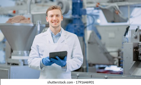 Young Male Quality Supervisor or Food Technician is Inspecting the Automated Production at a Dumpling Food Factory. Employee Uses a Tablet Computer for Work. He Looks to the Camera and Smiles.