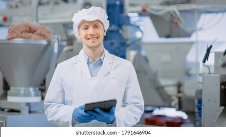 Young Male Quality Supervisor or Food Technician is Inspecting the Automated Production at a Dumpling Food Factory. Employee Uses a Tablet Computer for Work. He Looks to the Camera and Smiles.