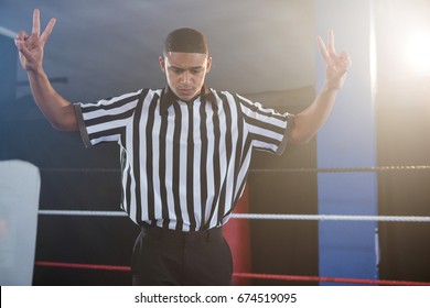 Young male referee gesturing while looking down in boxing ring at fitness studio - Powered by Shutterstock