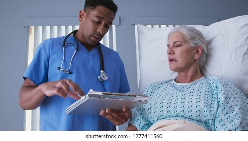 Young Male Registered Nurse Reviewing Health Record With Senior Female Patient