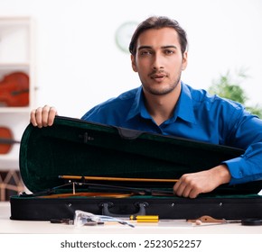 Young male repairman repairing violin - Powered by Shutterstock