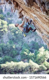 Young Male Rock Climber Looking Up On Challenging Route On Overhanging Cliff