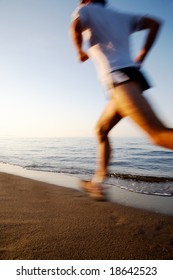 Young Male Runner Running On A Empty Beach At Dawn. Blur Effect.