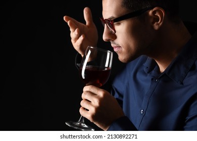 Young Male Sommelier Tasting Wine On Dark Background