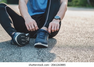 Young male in sportswear tying shoelace in the park outdoor, athlete runner man ready for running and jogging in morning. Exercise, wellness, healthy lifestyle and workout concept