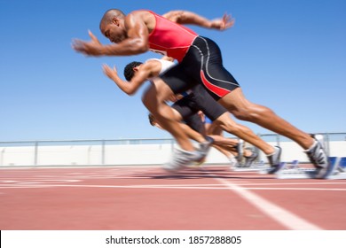 Young male sprinters starting a sprint race from their starting blocks on a bright, sunny day at the track