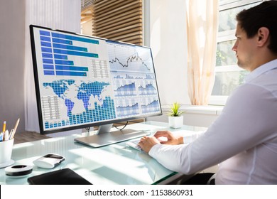 Young male stock market broker analyzing graph on computer at workplace