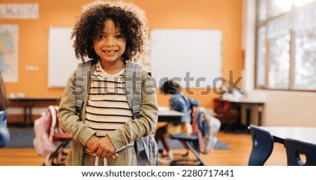 Young male student smiling and looking at camera on first day of co-ed class. Elementary school kid standing with his school bag on his back, ready to start a new year of learning. Foto stock © 