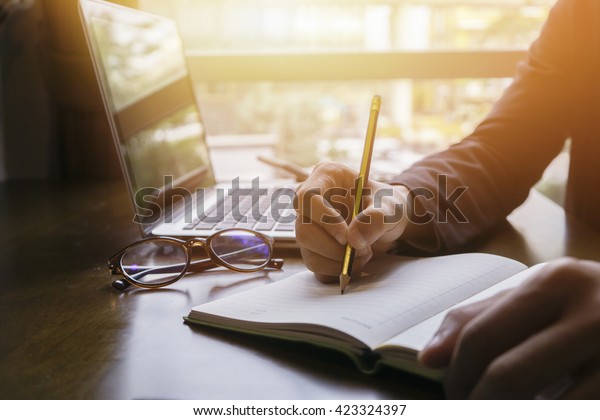 Young male student writes information from portable\
net-book while prepare for lectures in University campus,hipster\
man working on laptop computer while sitting in cafe,vintage\
color,selective focus