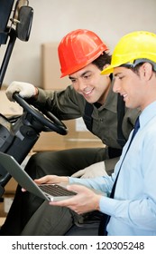 Young male supervisor and forklift driver using laptop at warehouse - Shutterstock ID 120305248