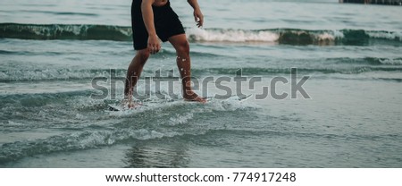 A young male surfer in blue boardshorts on a surfboard in Hua HIn Beach Thailand
