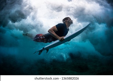 Young male surfer dives under the broken wave with his surfboard