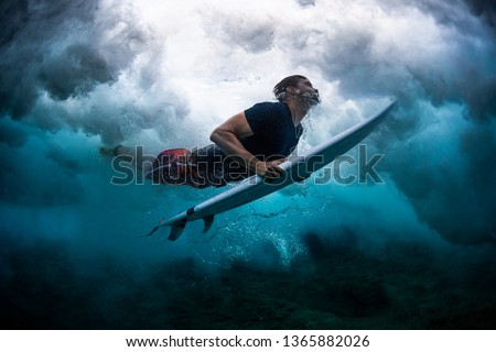Young male surfer dives under the broken wave with his surfboard