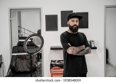 Young Male Tattoo Artist With Beard Looking Positive And Happy Standing And Smiling In Workshop Place.