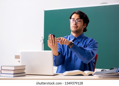 Junge männliche Lehrerin vor der Tafel