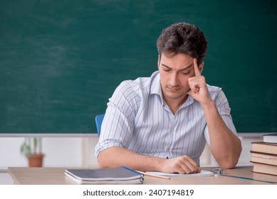 Young male teacher in front of green board - Powered by Shutterstock