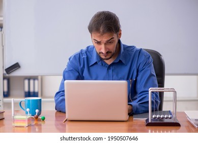 Young Male Teacher Physicist Sitting In The Classroom