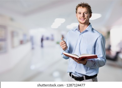 Young Male Teacher   Standing With Book