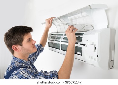 Young Male Technician Cleaning Air Conditioning System At Home